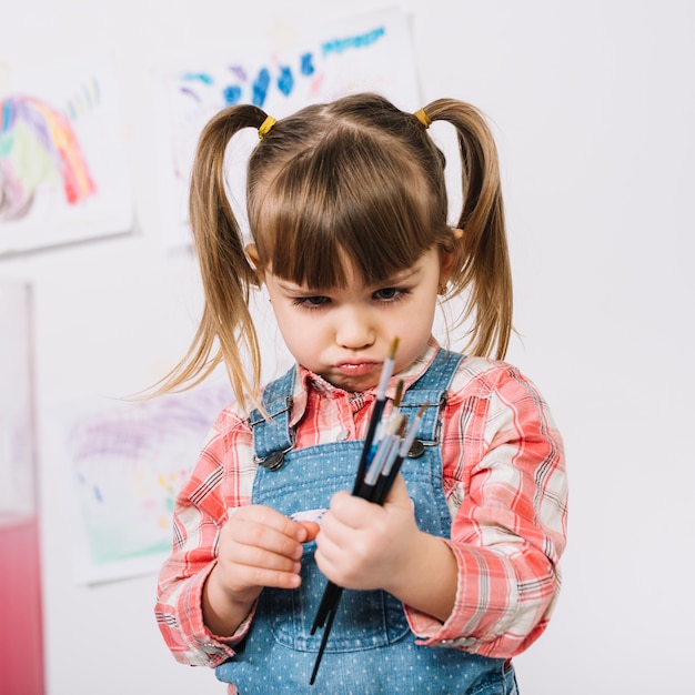 写真 手でペイントブラシで立っている気分を害する少女