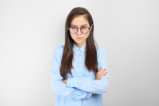 Offended Kazakh nerd student girl with displeased face and arms folded looks upset at camera in white studio isolated