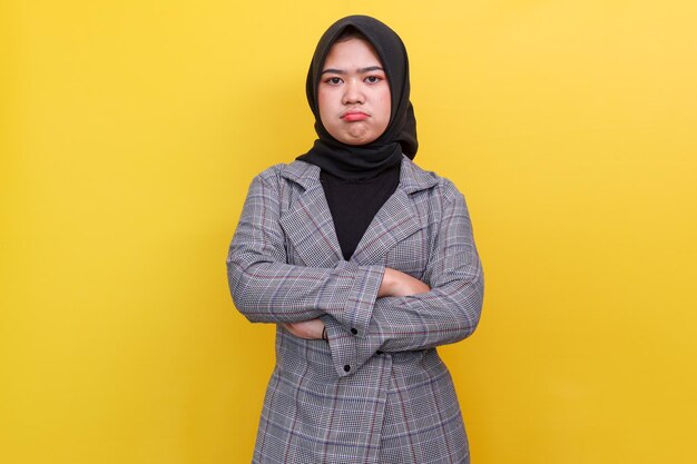 Offended sad angry woman in hijab with folded arms looking at camera isolated over yellow background