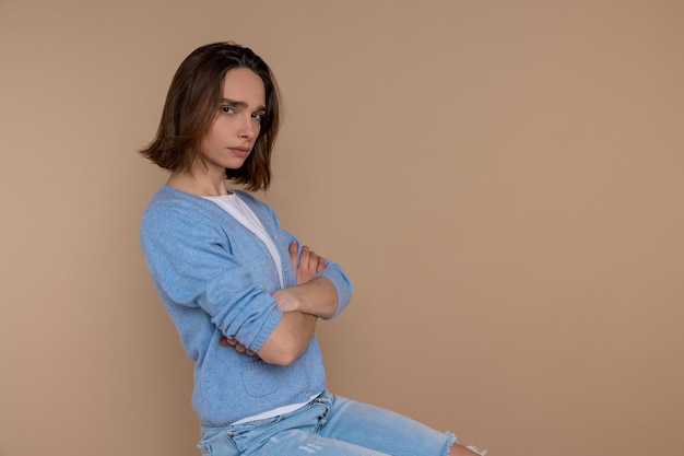 Photo offended sad unhappy woman in casual clothing looking at camera with folded hands isolated over beige background