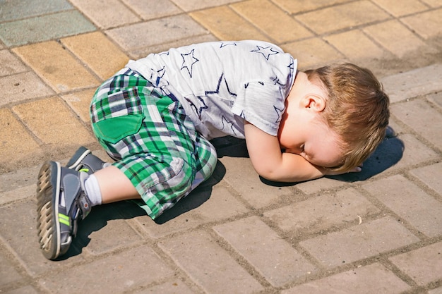 Offended small child is lying on asphalt