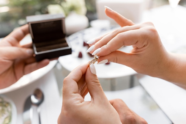 Foto un'offerta di matrimonio fede nuziale con una mano il ragazzo mette l'anello sulla mano della sua amata