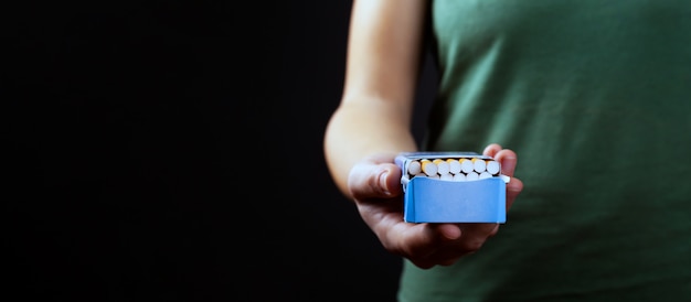 Offer smoking, pack of cigarettes in hand on dark