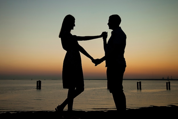 Offri la tua mano e il tuo cuore sulla spiaggia sullo sfondo di un bellissimo tramonto, fidanzamento un uomo dà un anello e chiede a una ragazza di sposarsi, lei è felice