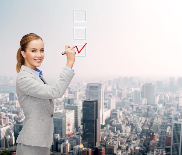 office, business and new technology concept - smiling businesswoman writing something in the air with marker