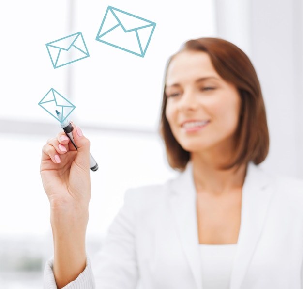 office, business, technology concept - businesswoman drawing envelopes in the air with marker