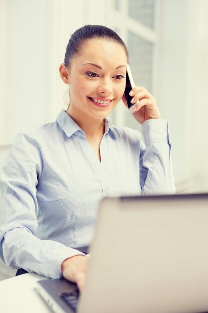 office, business and technology concept - smiling businesswoman with laptop computer and smartphone