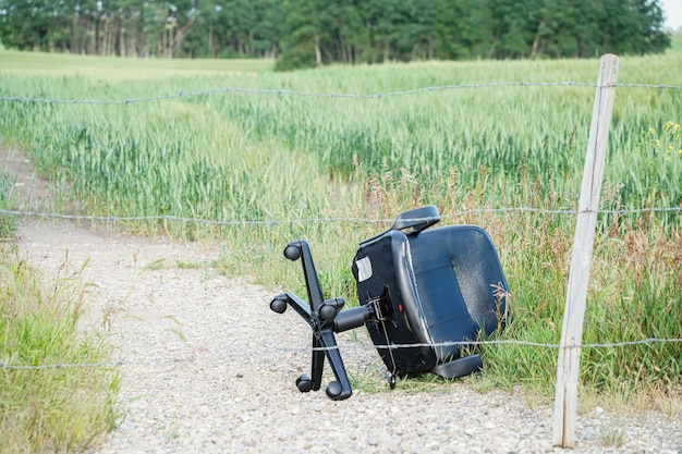 Office chair disposed of at a farm field