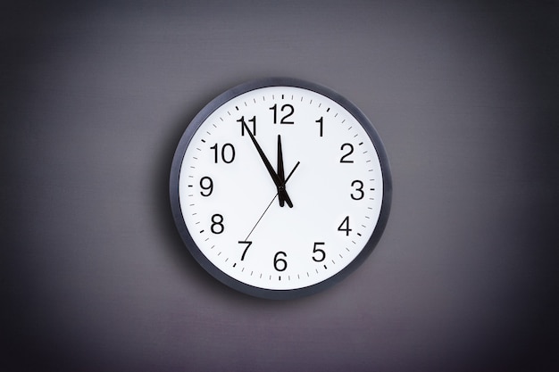 Office clock against black wall background with vignette