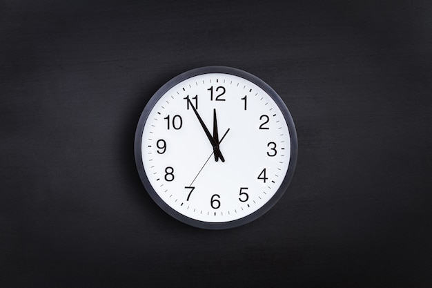 Office clock showing 5 minutes to midnight against black chalkboard background