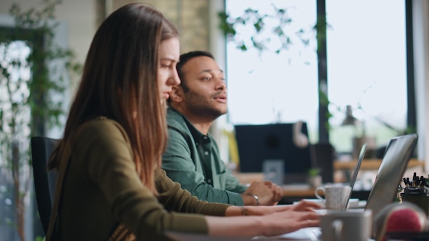 Office coworkers brainstorming sitting conference room with laptops close up