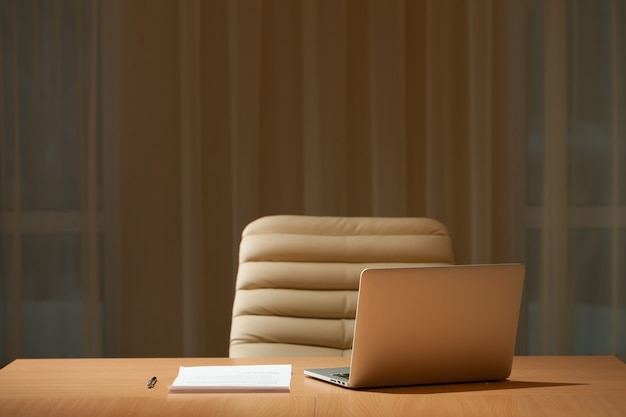 Office desk in empty room, laptop computer on table