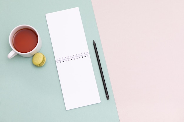 Office desk mock up template with clean notebook, keyboard and Cup of tea and macaroon 