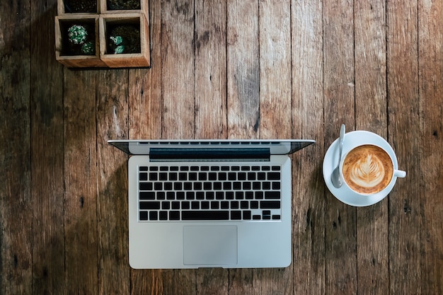 オフィスデスクモックアップ：ラップトップコンピュータ、スマートフォン、木製の机のコーヒー