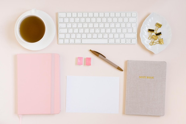 オフィス デスク ノート キーボードと色鉛筆ベージュ色の背景にお茶のミモザの花のカップ女性のための最小限のビジネス コンセプト