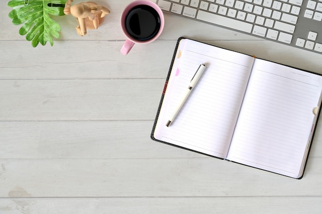 Office desk open notebook with keyboard,  coffee mug, notebook and office supplies