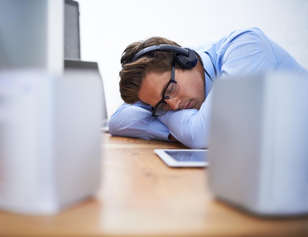 office desk sleep and business man tired after working on project software system or coding tech script or programming programmer burnout developer fatigue and sleeping person listening to music