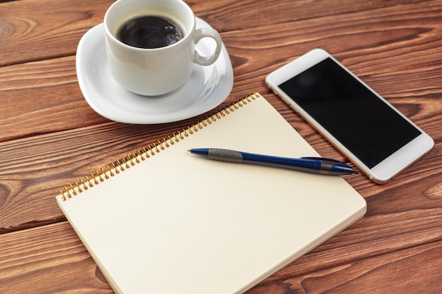 Office desk table top view. Notepad with blank pages on wooden table