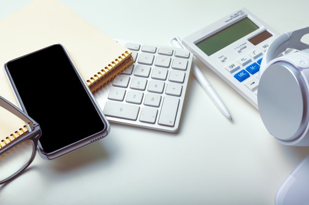 Office desk table with computer keyboard, supplies, calculator, pen, glasses 