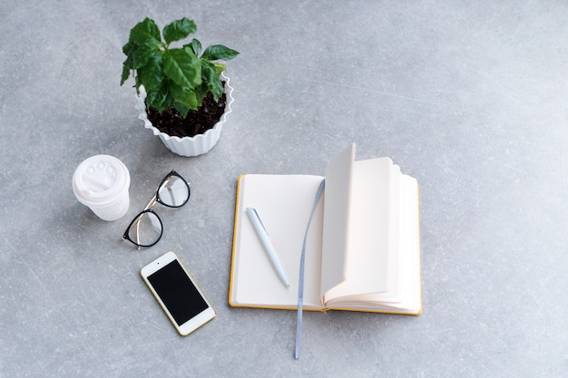 Office desk table with notebook planner, smart phone, glasses and coffee cup.