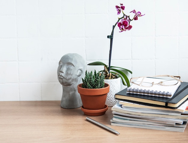 Office desk table with  notebooks, supplies and houseplants