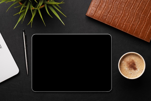 Фото Офисный стол с планшетным ноутбуком, чашкой кофе и принадлежностями