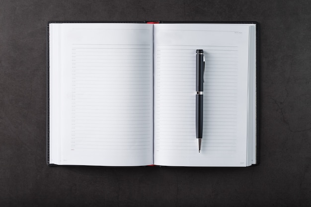 Office desk with black notepad and pen