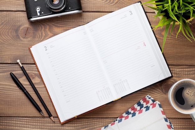 Office desk with calendar notepad camera supplies and flower