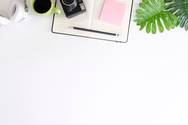 Office desk with camera, pencil, notepaper and headphones with coffee on workspace