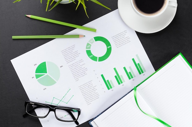 Office desk with charts coffee plant and notepad