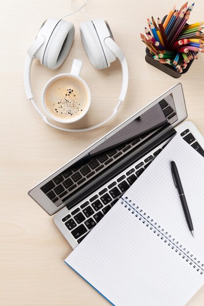 Office desk with laptop coffee and headphones