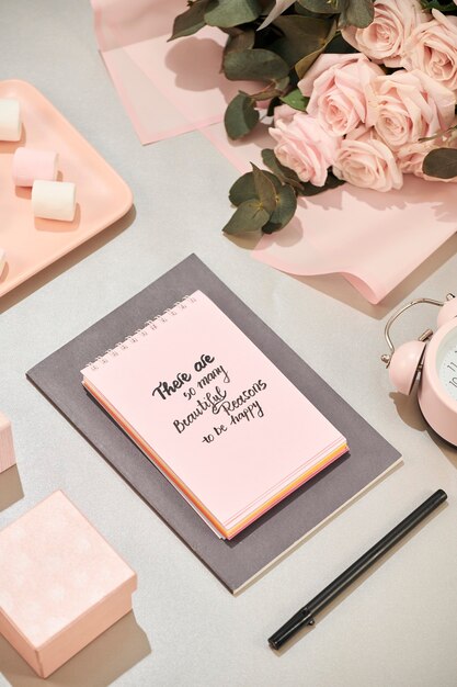 Office desk with notebook, beautiful bouquet of roses on pink