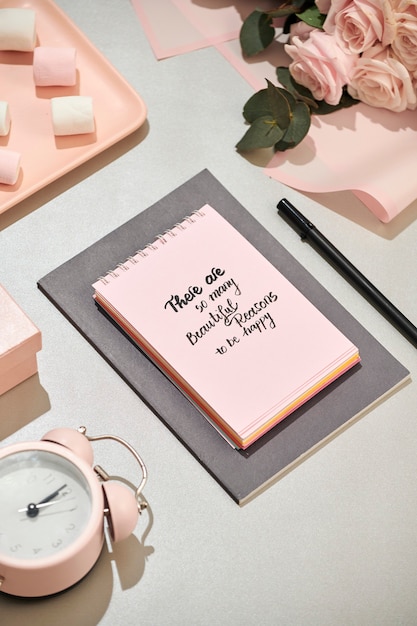 Office desk with notebook, beautiful bouquet of roses on pink