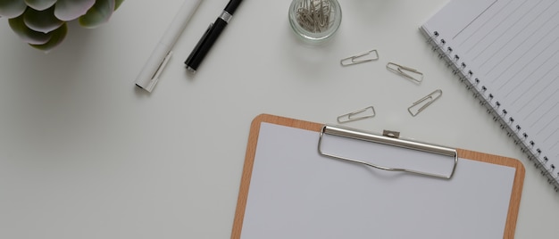 Office desk with paper on clipboard, stationery, schedule book and other office supplies