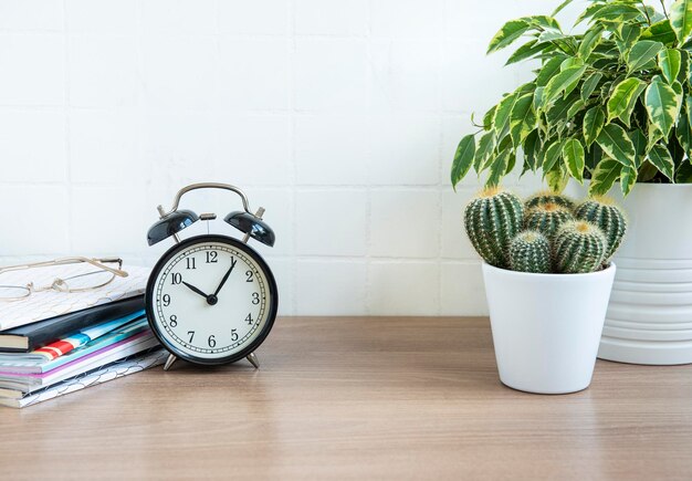 Photo office desk with stack of notepads alarm clock office supplies and house plants