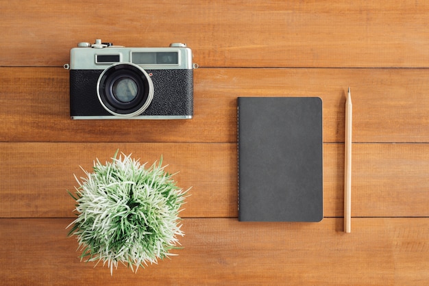 Office desk wooden table with old camera and tree and notebook. Top view with copy space