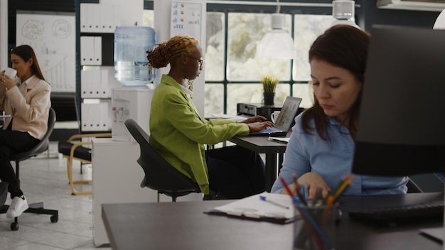 Office employee reading annual data report on screen, checking analytics before planning new company investment at desk. Young woman analyzing internet statistics, profit growth.