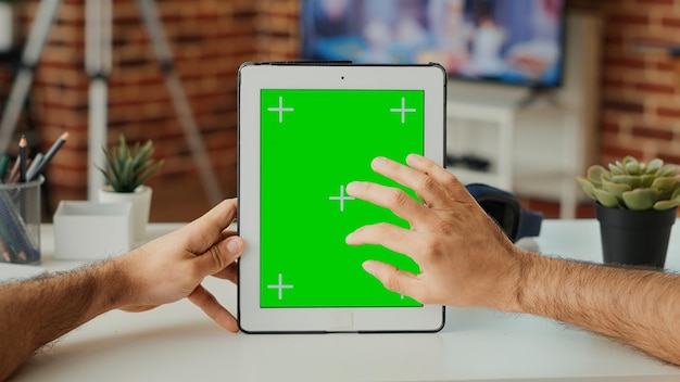 Office employee using digital gadget with greenscreen template,\
vertically holding portable tablet with isolated display. working\
with blank chroma key background and mock up screen. close up.