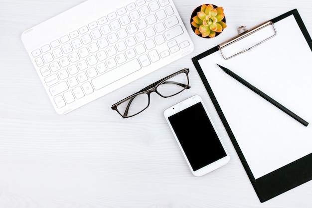 Office flatlay met wit toetsenbord, leesbril, huisdier en notebook