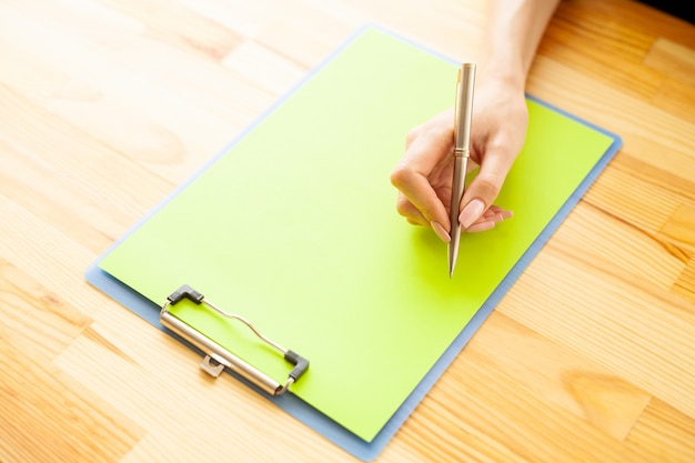 Office Hand met een map met een groene kleur papier en pen op de achtergrond van de houten tafel