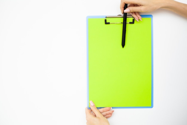 Office-hand met een map met een groene kleur papier en pen op de achtergrond van de witte tafel. Copyspace.