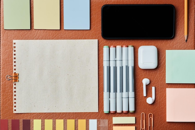 Office knolling composition of drawing markers wireless earphones sticky notes gadget on leather sur