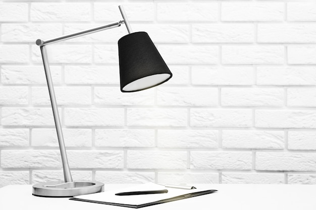 Office lamp on the desk on brick wall background