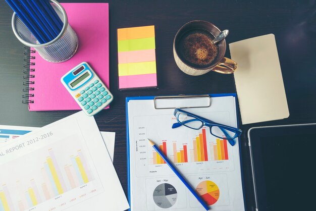 Office laptop business financial document chart and graph on wooden table with coffee cup