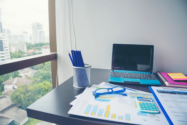 Office laptop business financial document chart and graph on wooden table with coffee cup