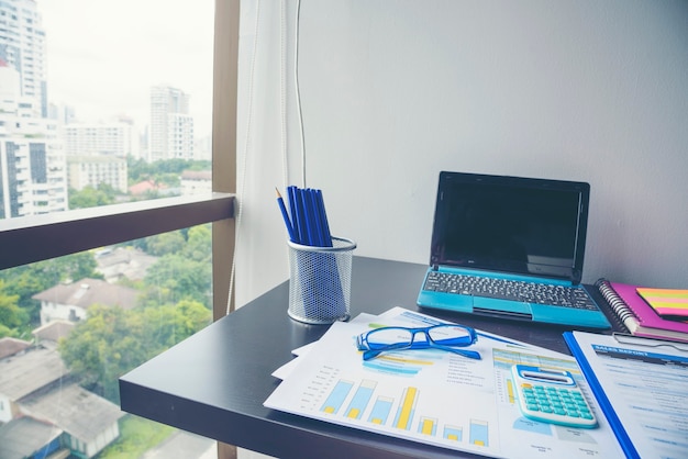 Office laptop business financial document chart and graph on wooden table with coffee cup.
