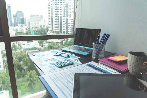 Office laptop business financial document chart and graph on wooden table with coffee cup
