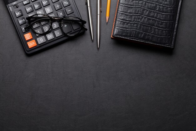 Photo office leather desk table with calculator glasses notepad pen and pencil top view with copy space