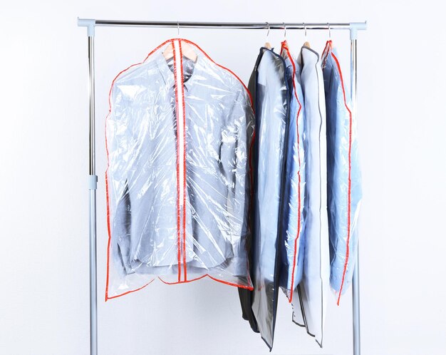 Office male clothes in cases for storing on hangers on gray background