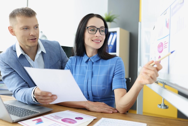 In the office a man and a woman are looking at a board with a diagram closeup job indicator of